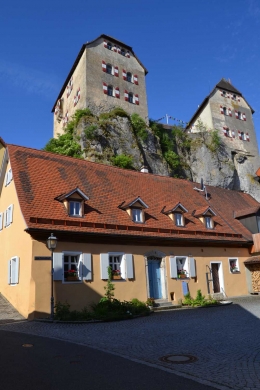 Ansicht von Norden gegen die Burg. Das Haus liegt unmittelbar am Fuß des Burgfelsens, am Weg zum Eingang der Burg